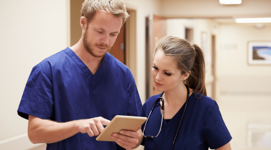 Medical staffing doctors reviewing documents on tablet, in hospital.